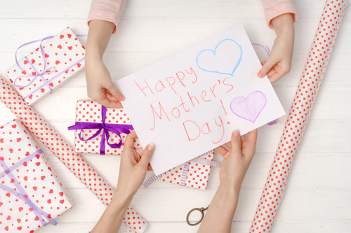 Biglietto Happy Mother’s Day realizzato a mano accanto a pacchi regalo