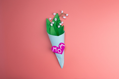 Bouquet stilizzato con cuore rosa e scritta Mom su sfondo rosa