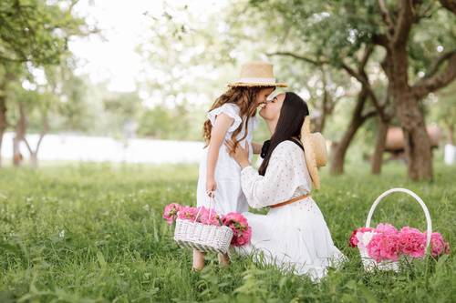 Mamma e figlia che fanno una passeggiata in un giardino con dei cestini di fiori