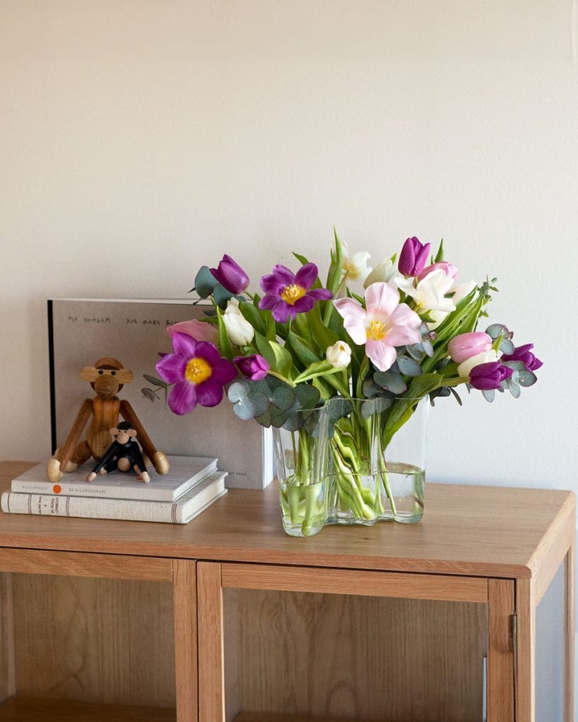 Tulipani viola e bianchi aperti in vaso di vetro.